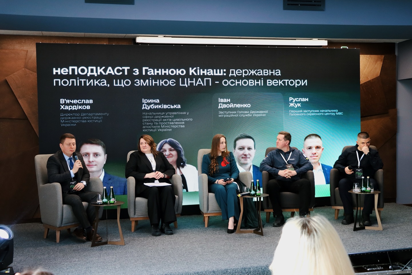 П'ять людей перебувають на сцені, на фоні - екран.