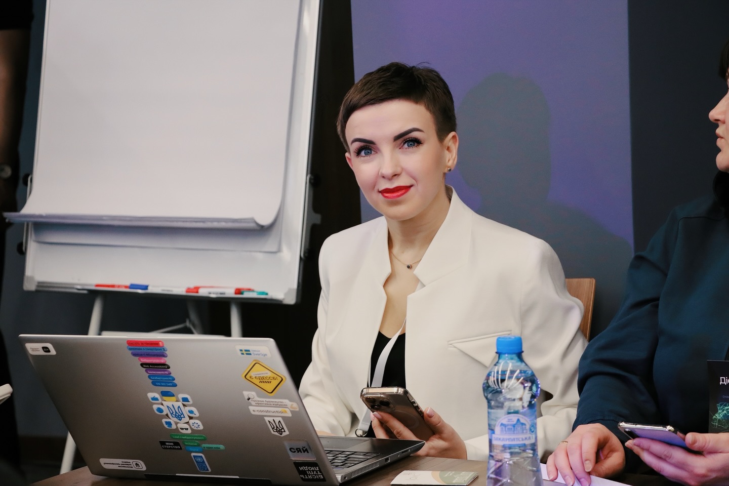 Жінка з короткою зачіскою посміхається.