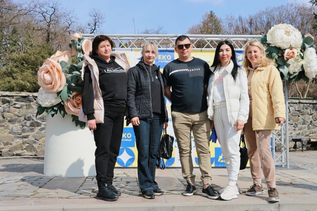 Чотири жінки та чоловік стоять на фоні банера.