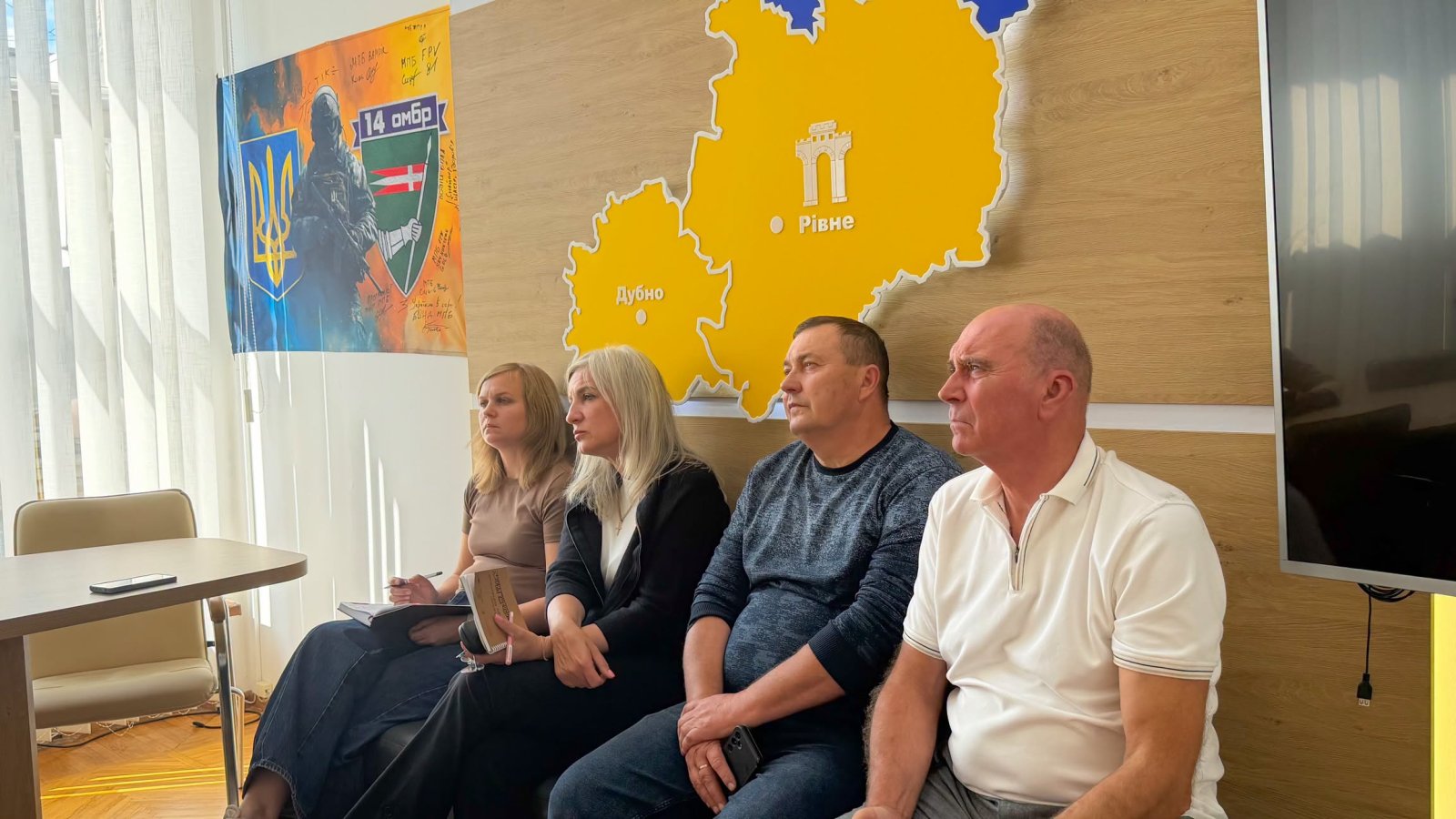 Дві жінки та два чоловіка сидять у кабінеті.