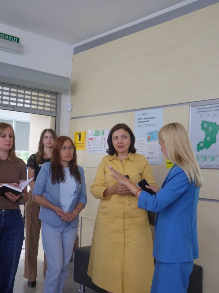 Жінка зі світлим волоссям показує щось групі жінок.