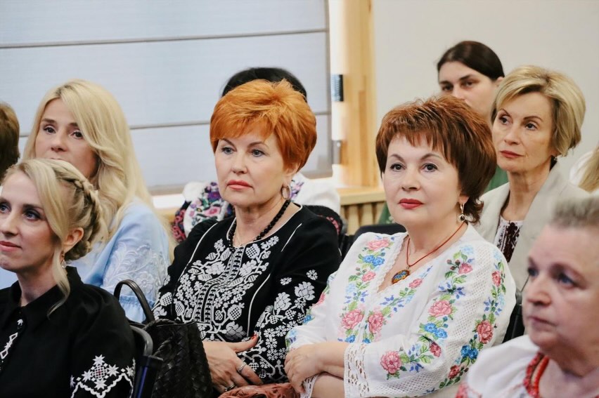 Жінки у вишиванках сидять у приміщенні.
