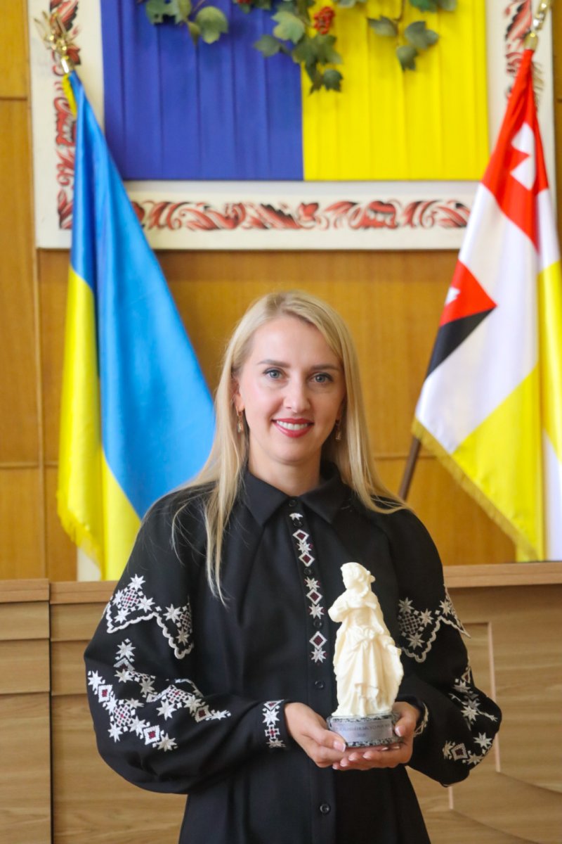Жінка у вишиванці тримає статуетку.