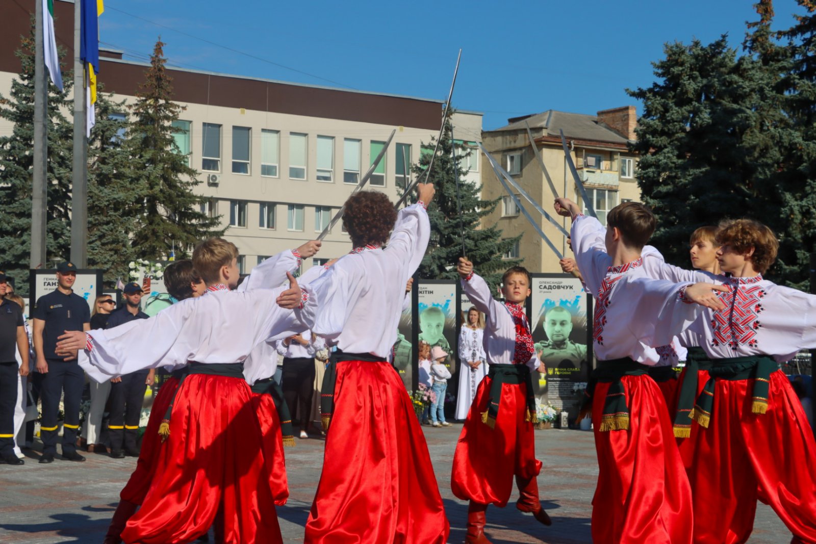 Хлопці в білих вишиванках та червоних шароварах з шаблями.