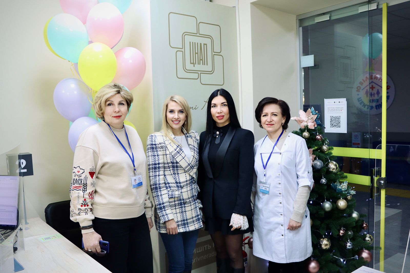 Чотири жінки позують для фото, у приміщенні.