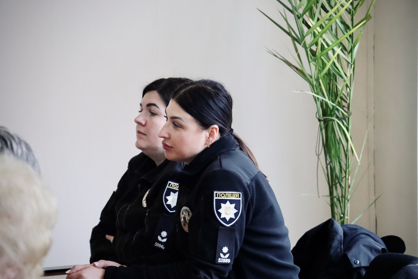 Дві жінки у чорному одязі сидять за столом.