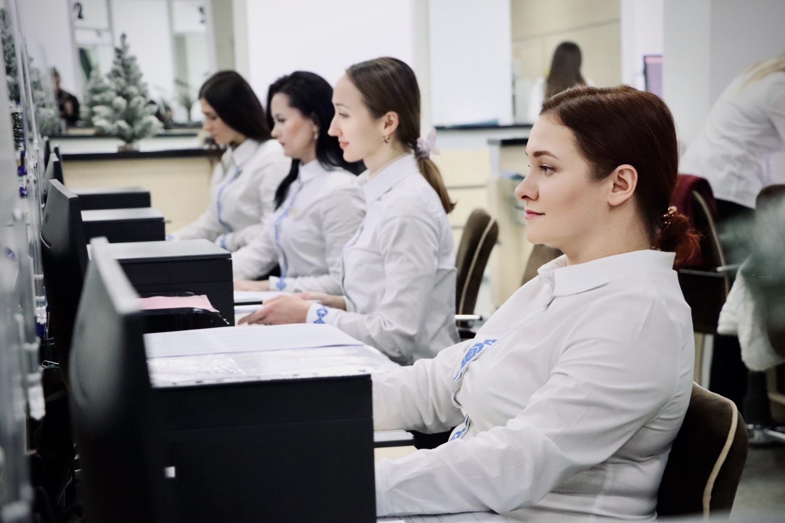 Чотири жінки у білому одязі сидять за комп'ютерами.