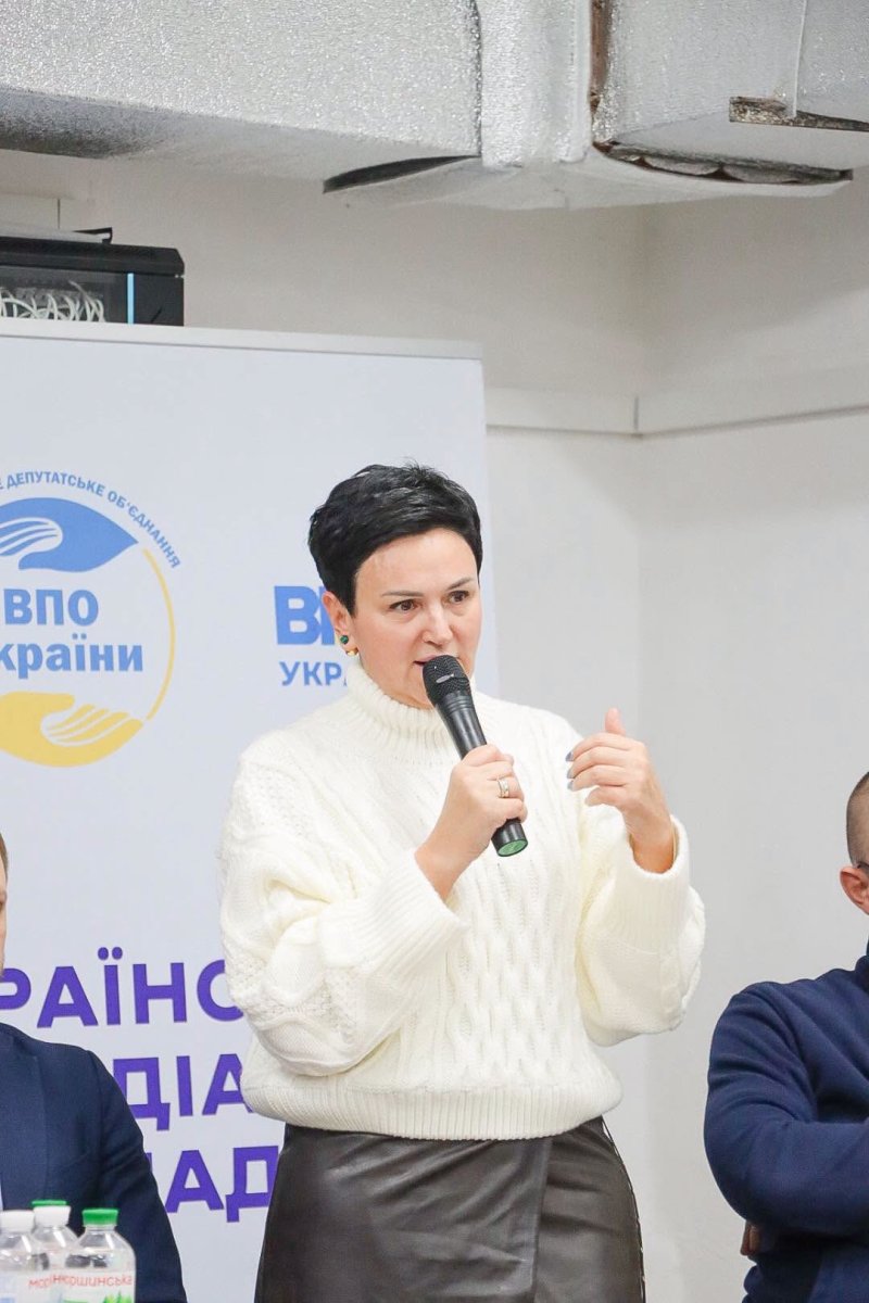 Жінка з коротким волоссям тримає мікрофон у руках.