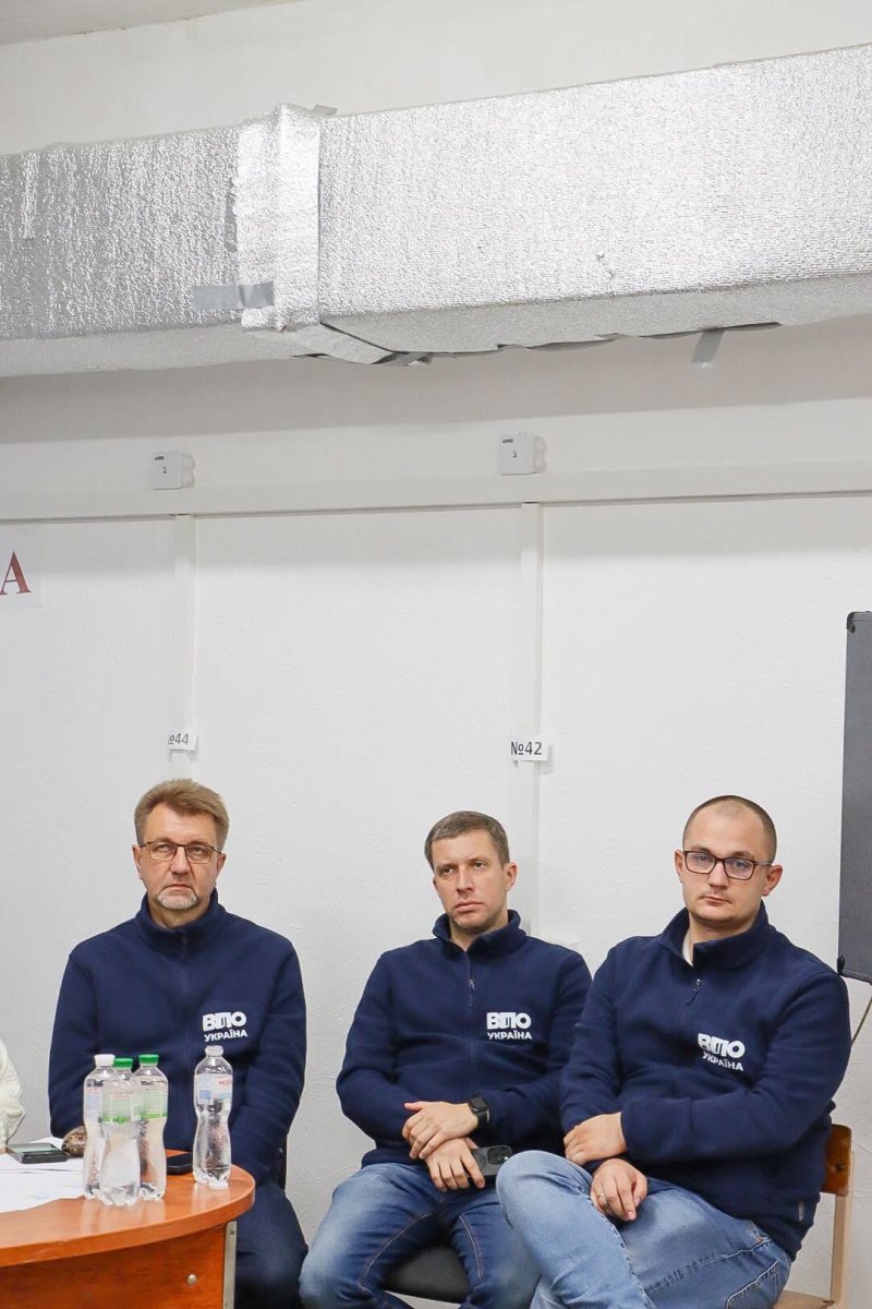 Троє чоловків сидять у приміщенні.