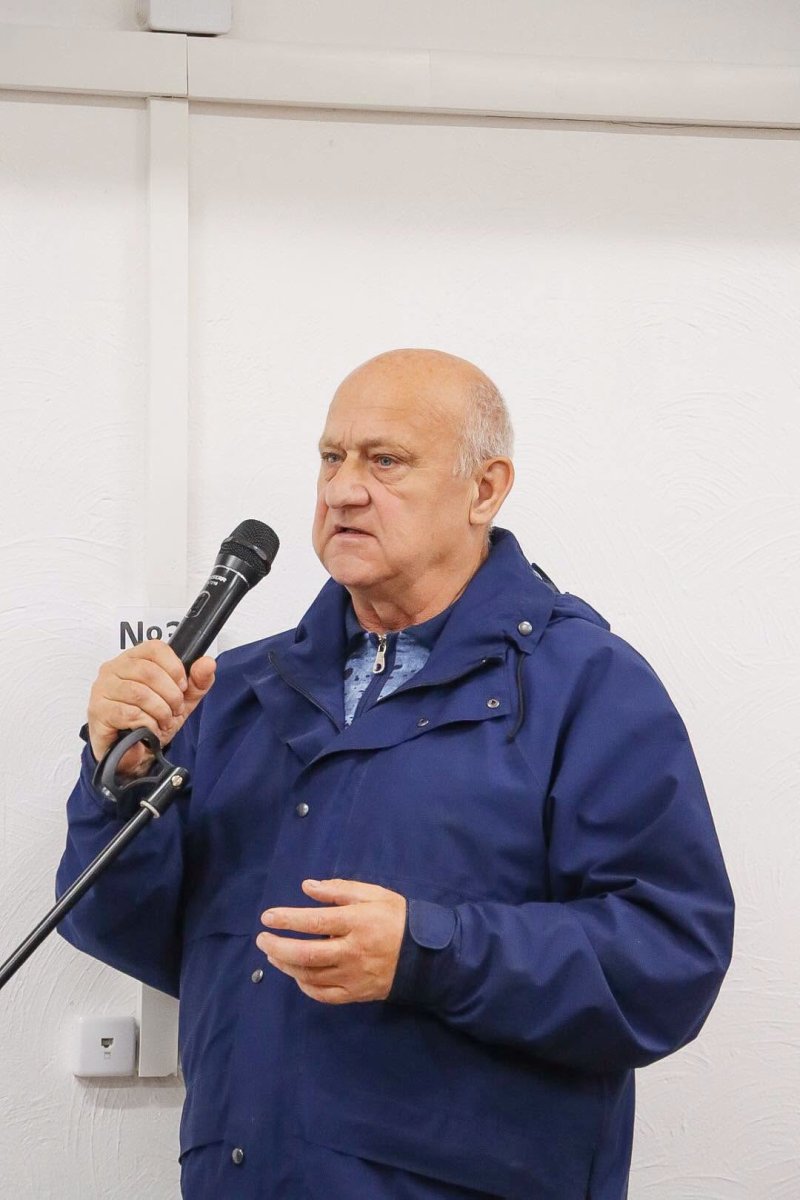 Чоловік старшого віку тримає мікрофон у руках.