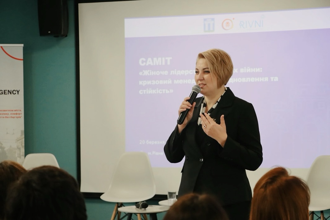 Жінка з коротким волоссям тримає мікрофон у руках.