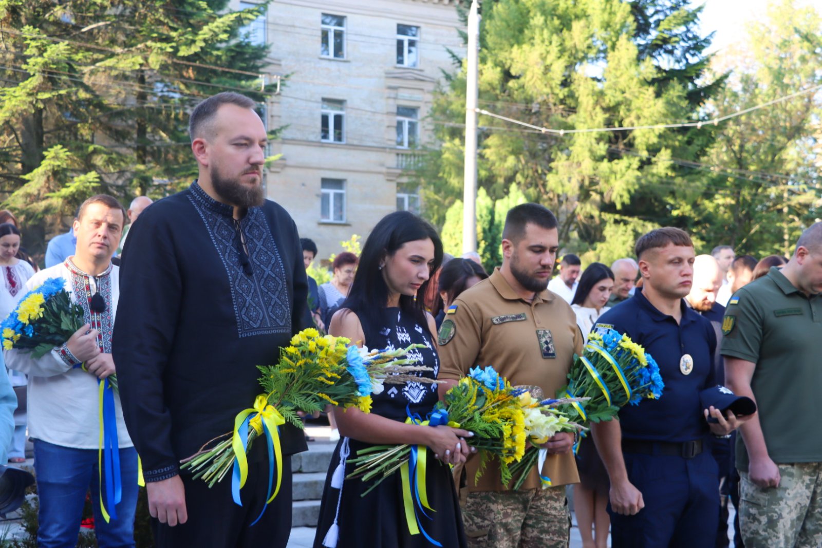 Жінка та троє чоловіків тримають квіти.