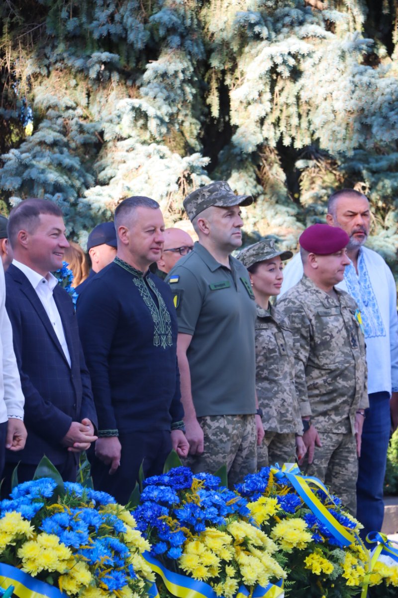 Група людей стоять біля жовтих та блакитних квітів.