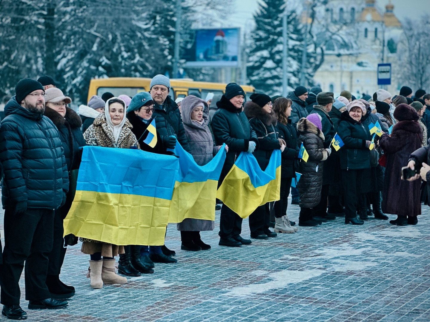 Група людей перебувають на дворі та тримають у руках прапори України 