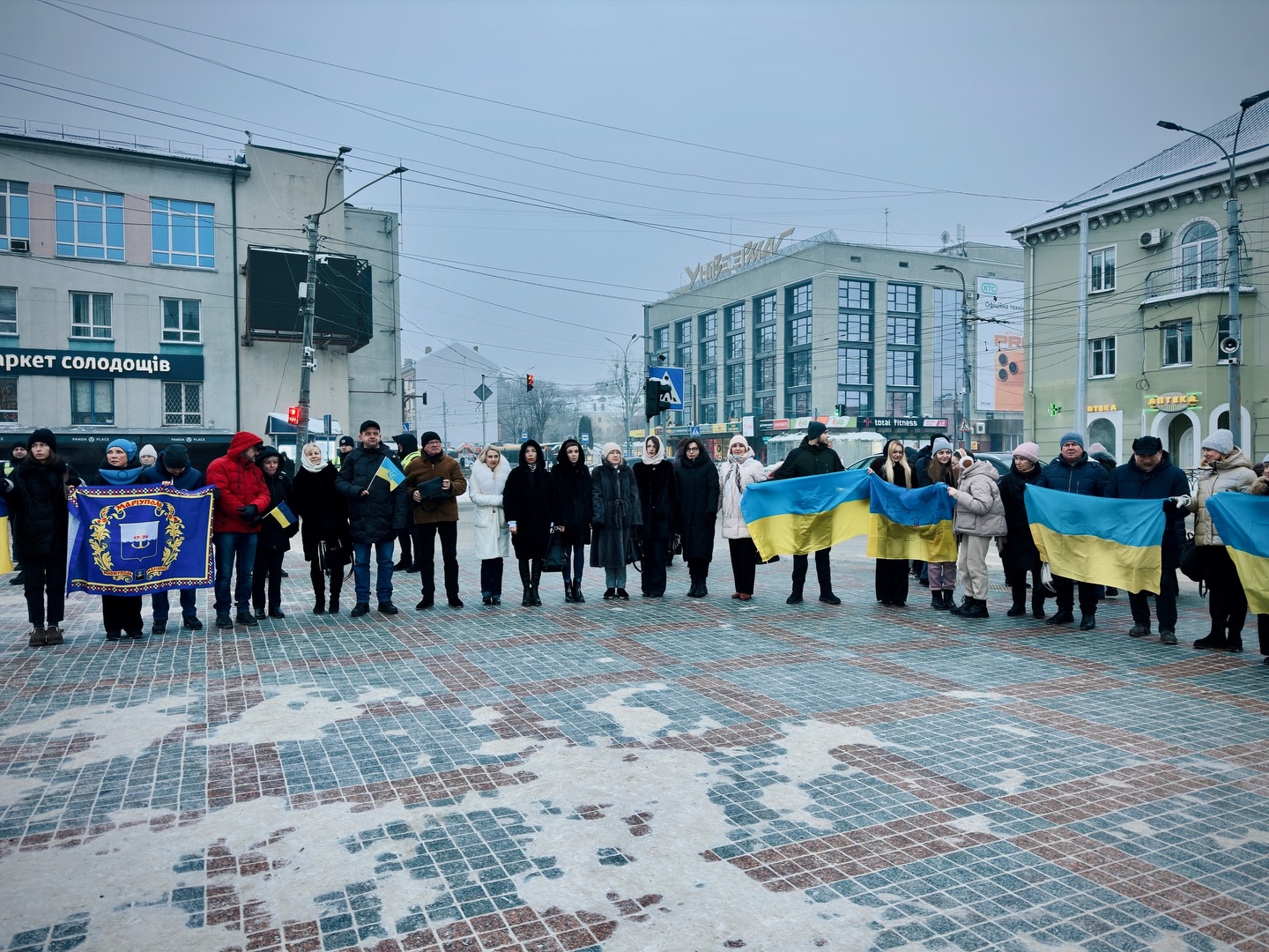 Багато людей перебувають на дворі та тримають прапори України 