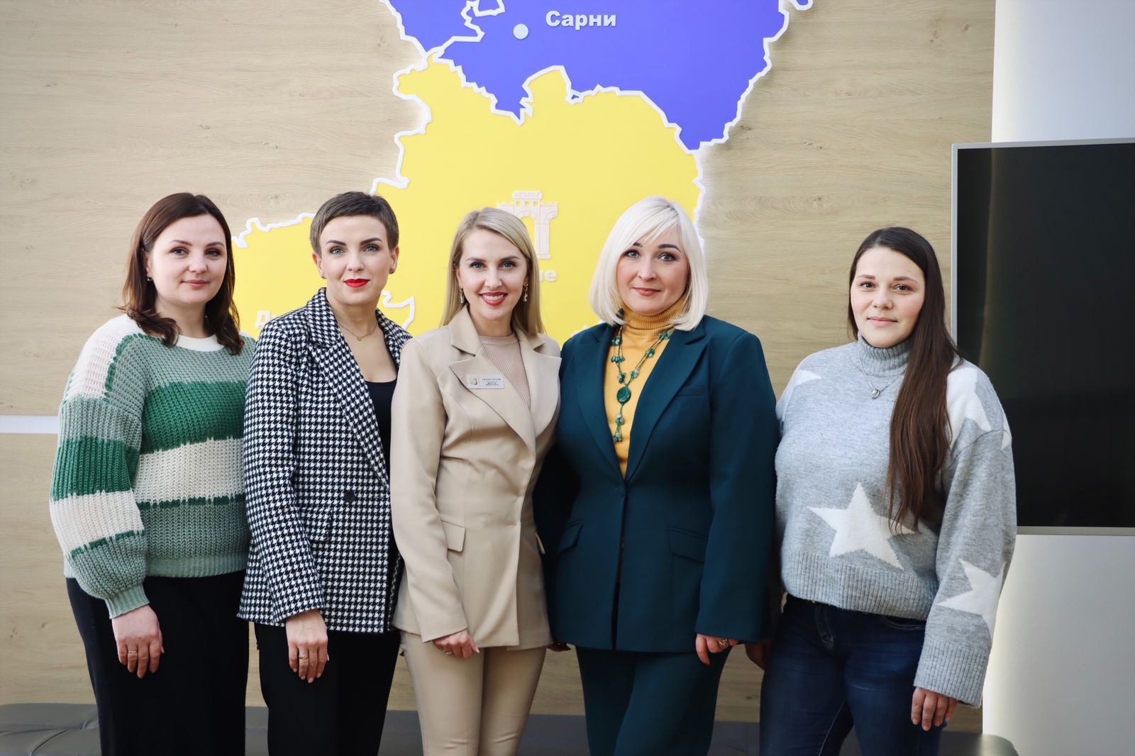 П'ять жінок позують для спільного фото у приміщенні.