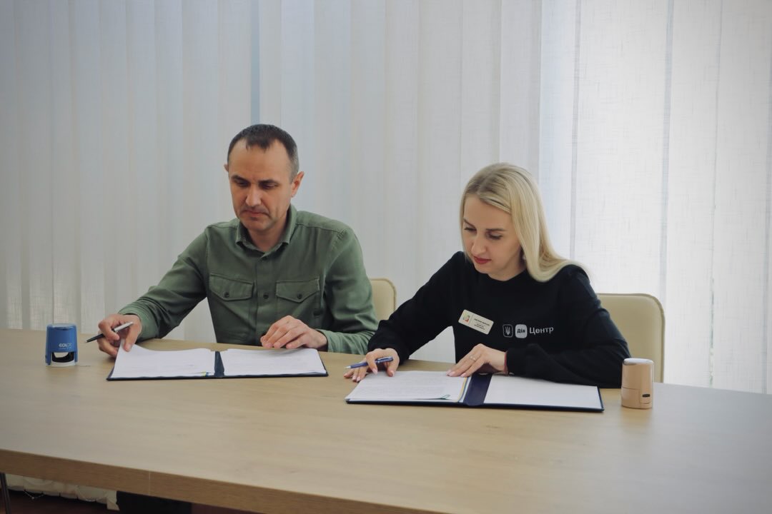 Чоловік та жінка сидять за столом, у приміщенні.