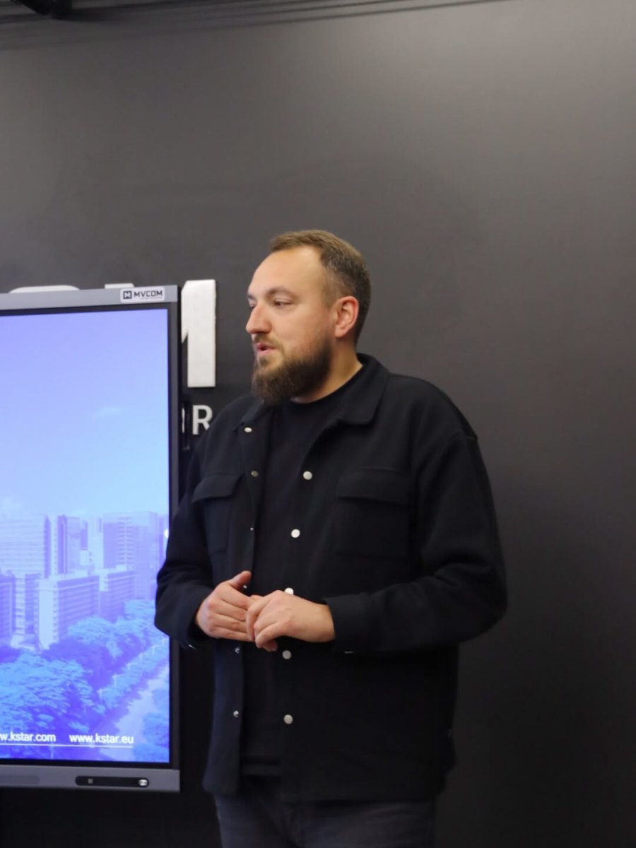 Чоловік з бородою стоїть у приміщенні.
