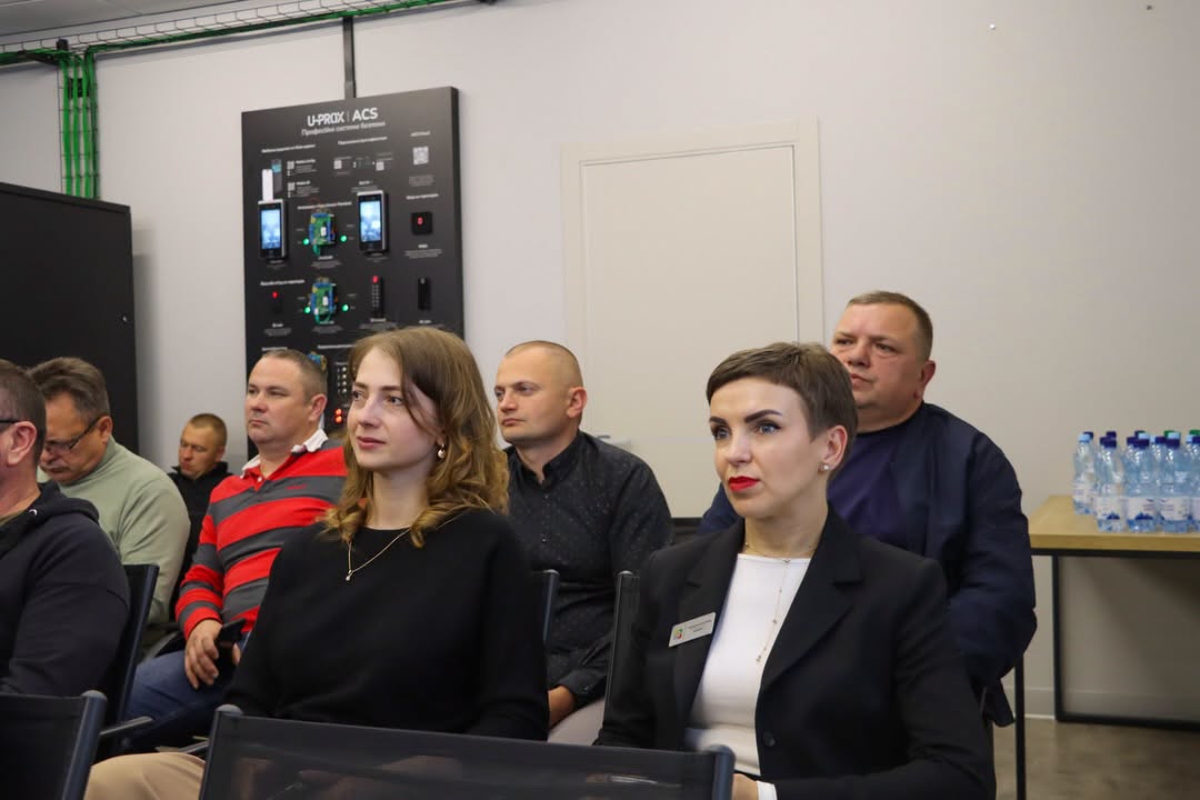 Група людей сидить у приміщенні, спереду - дві жінки.