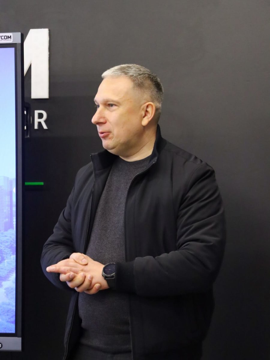 Чоловік у темному одязі стоїть у приміщенні.