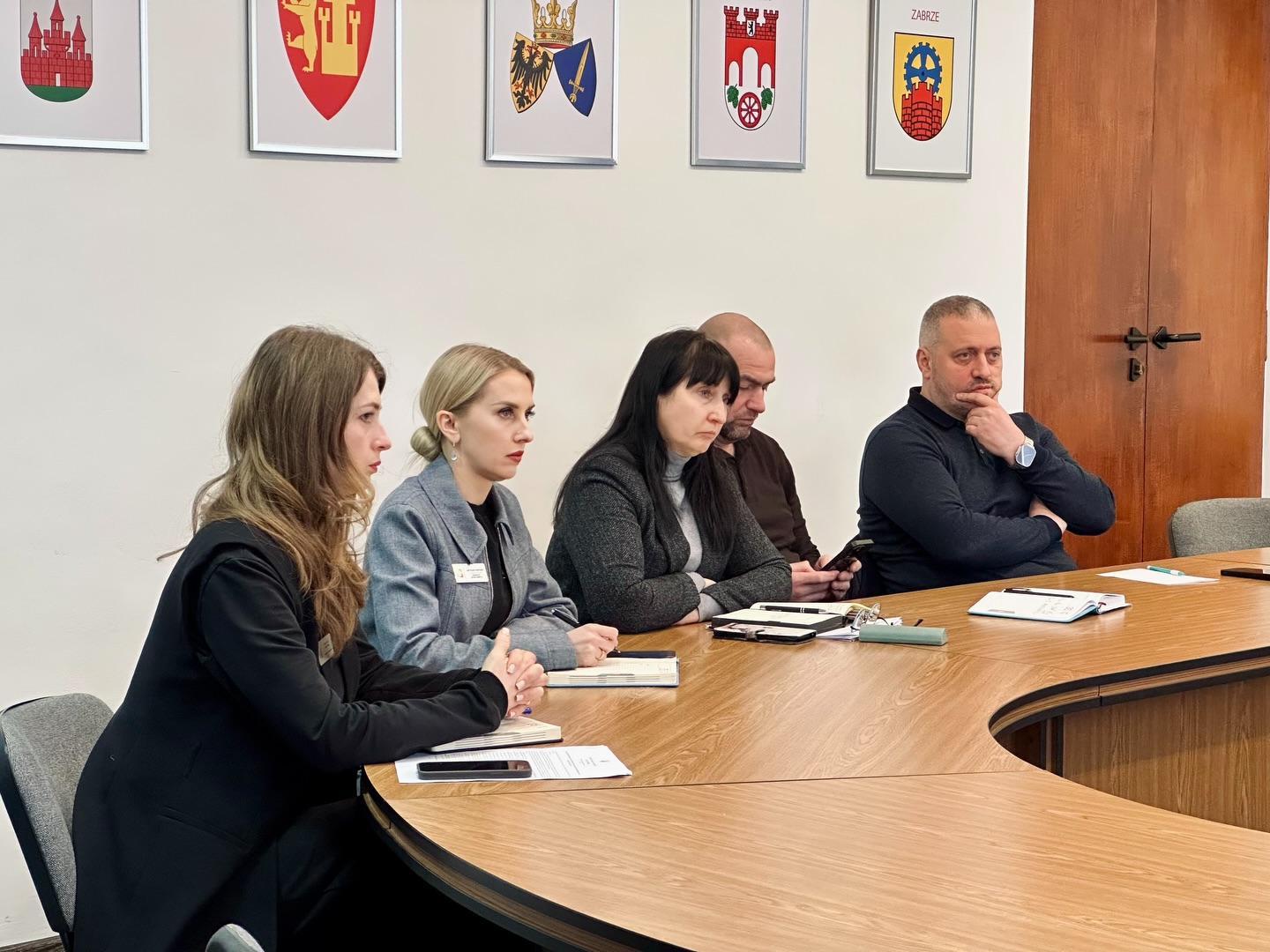 Три жінки та двоє чоловіків сидять за столом