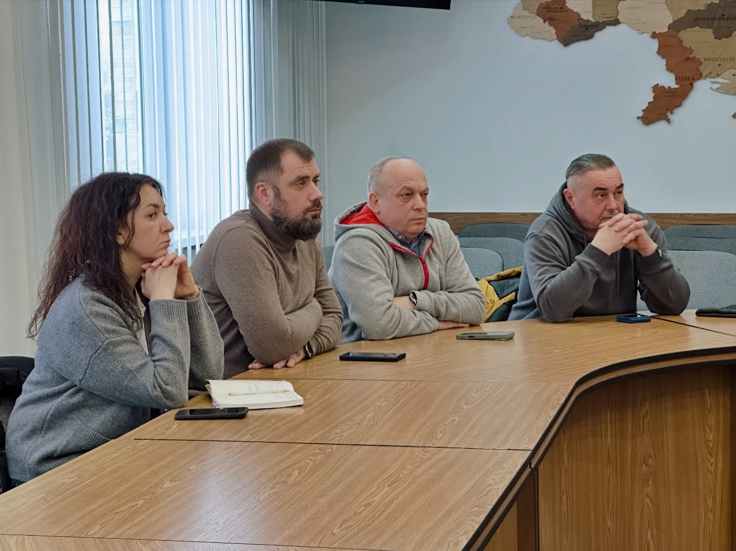 Три чоловіка та одна жінка сидять за столом