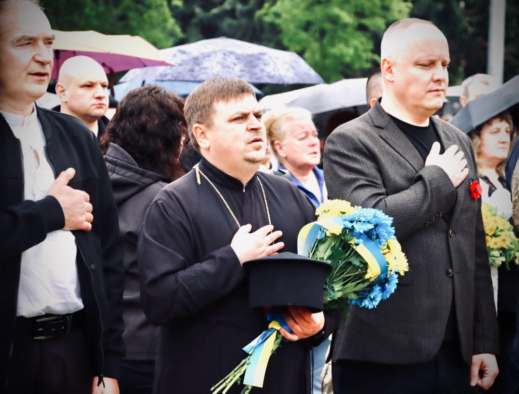 Троє чоловіків тримають руку на серці.