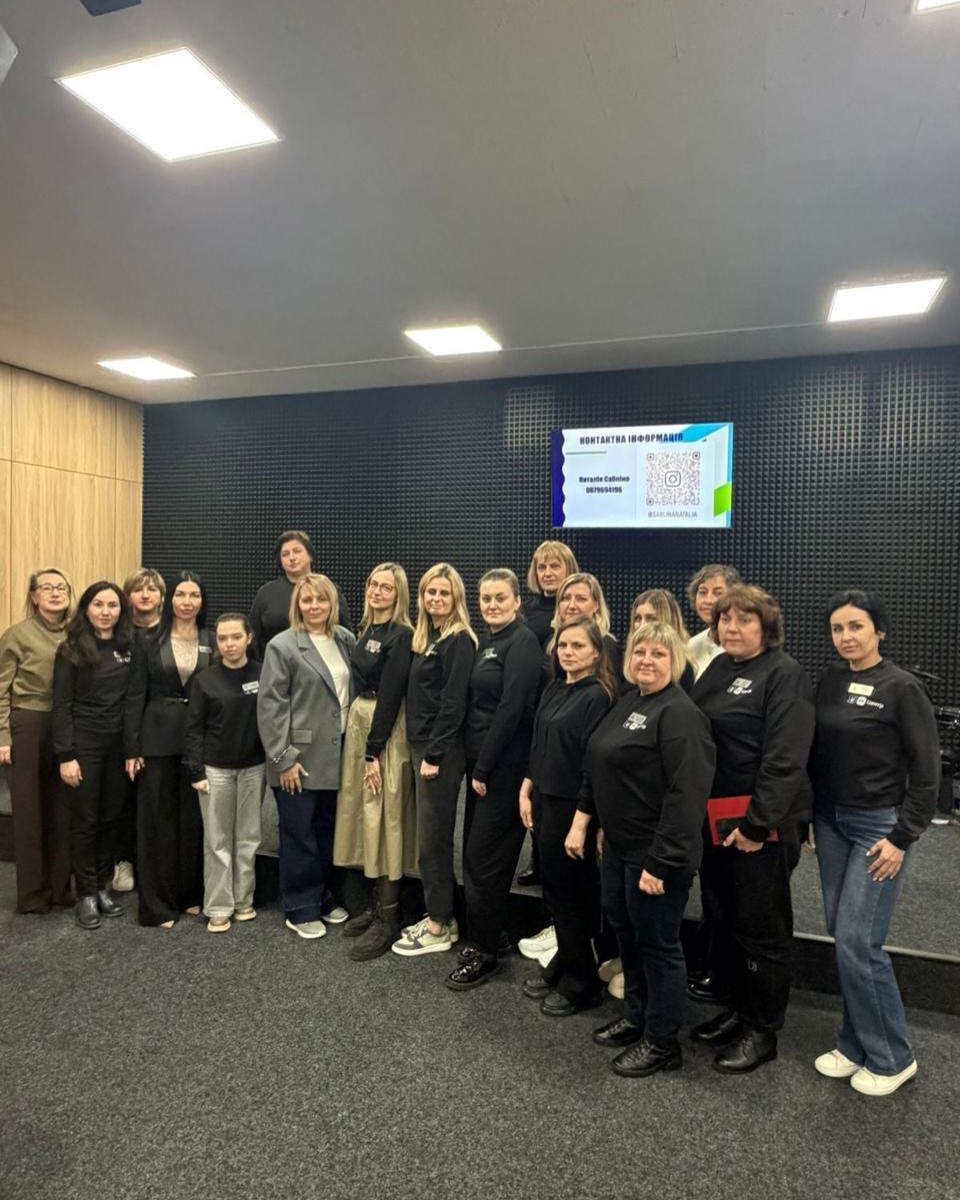 Групове фото жінок на фоні звукоізолюючої стіни та телевізору.