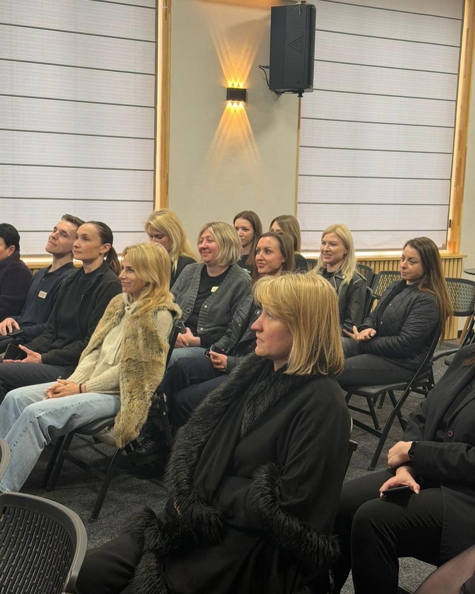 Група жінок сидить у залі.