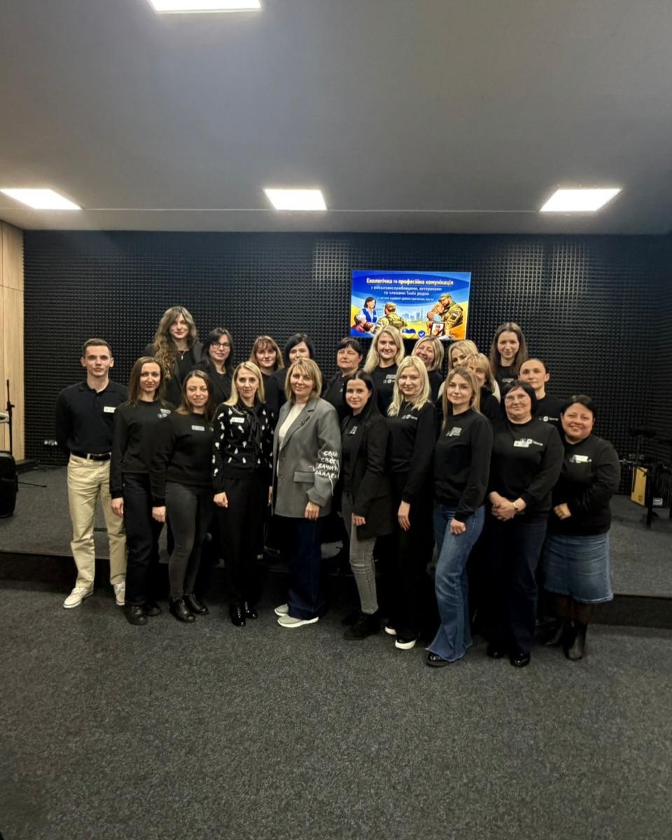 Групове фото у залі на фоні стіни.