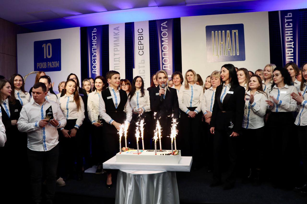 Багато людей перебуває у залі, перед ними торт