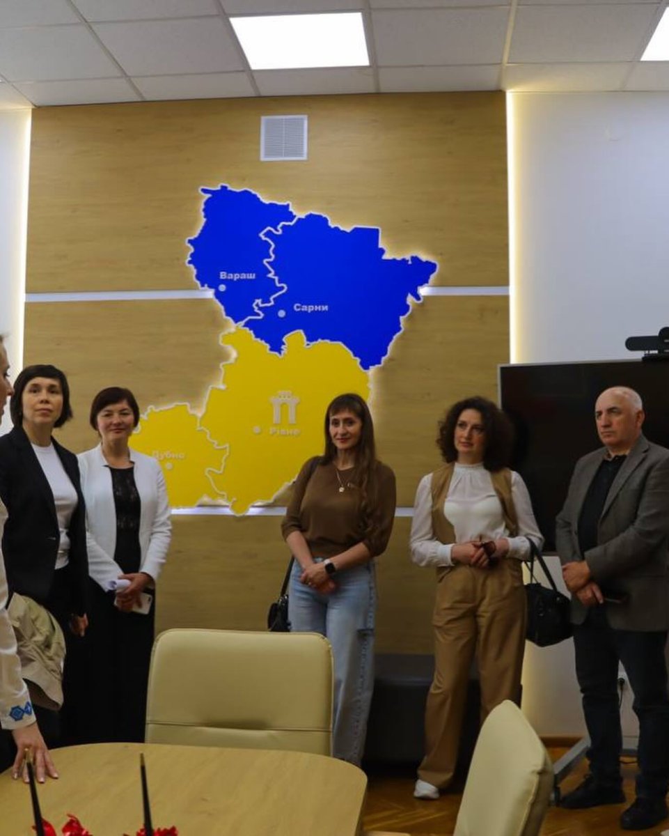 Чоловік та декілька жінок стоять у приміщенні, на фоні - карта Рівненщини.