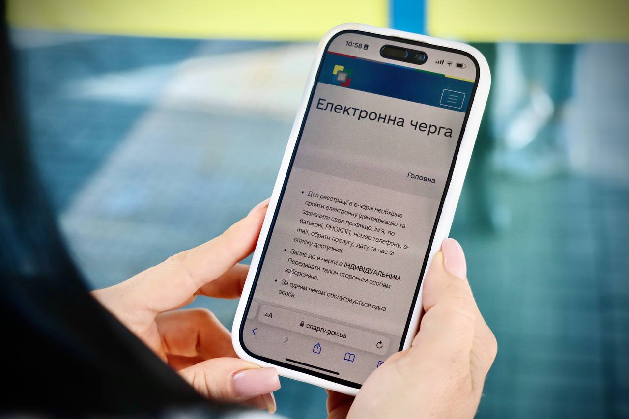 У руках смартфон із відкритою сторінкою «Електронна черга»..